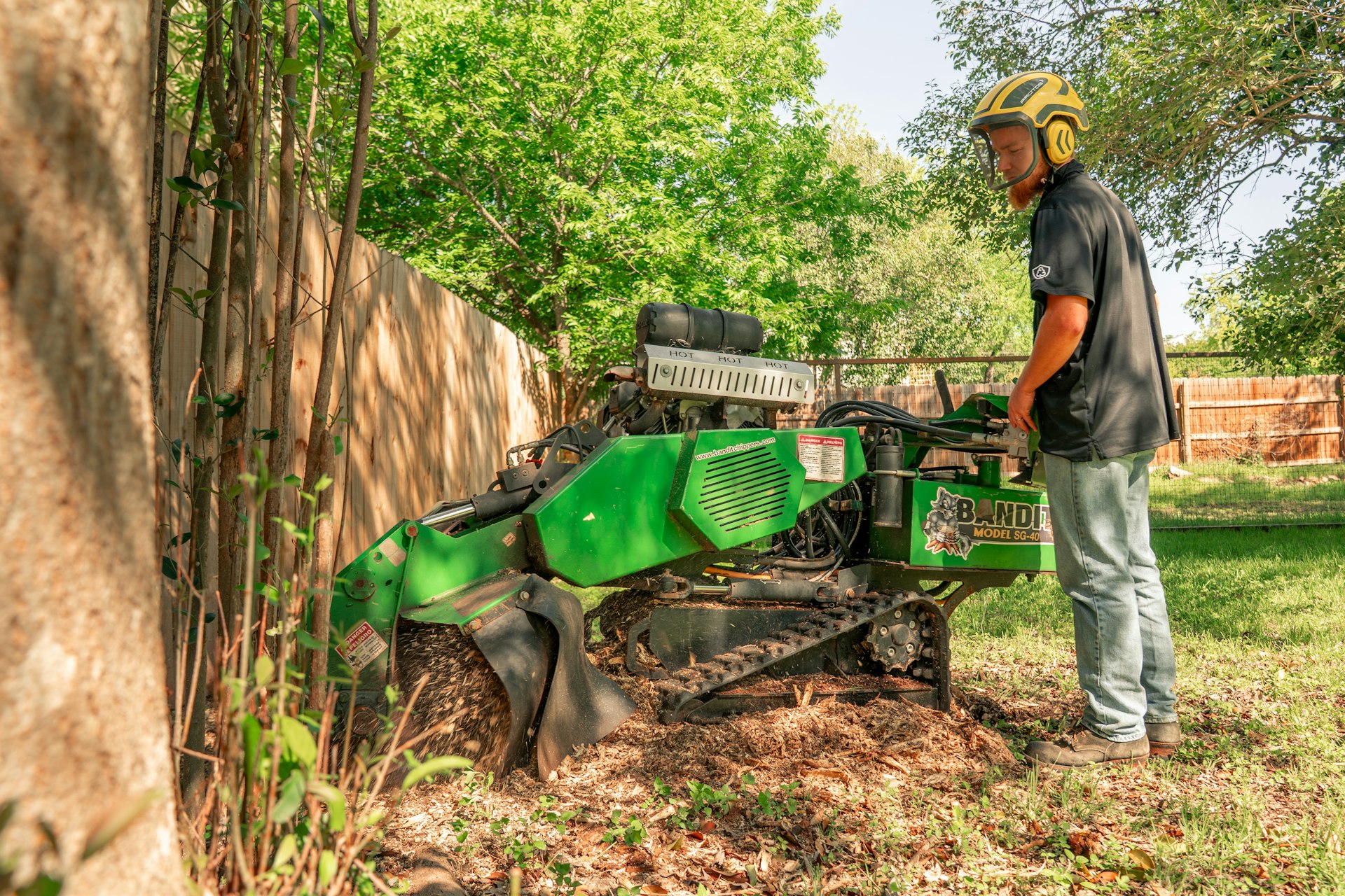 A worker operates a tree stump grinder.